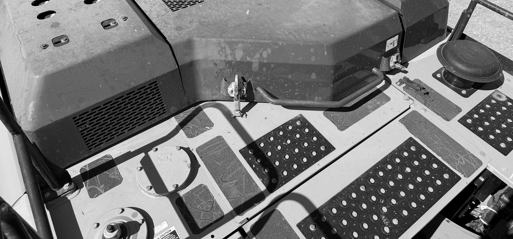 A gray engine cover with a perforated vent panel on top of a wheel loader