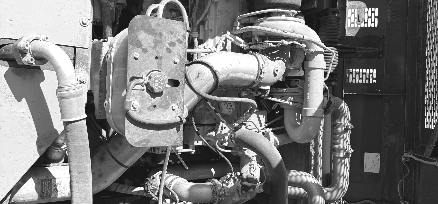 A turbocharger, intake pipe, and hoses packed into a machine's open engine bay