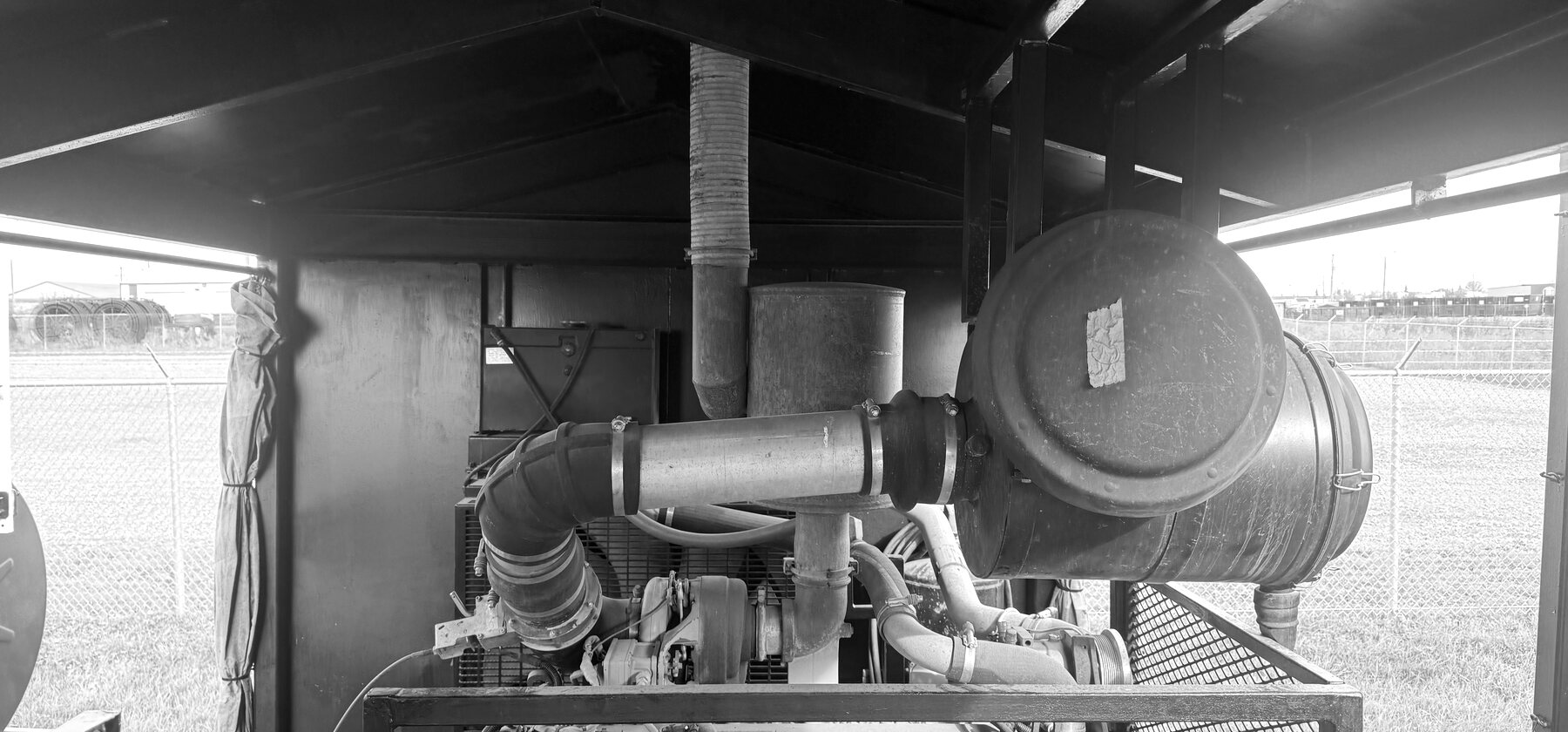 Ducting, a muffler, and hose clamps inside a shrouded generator enclosure