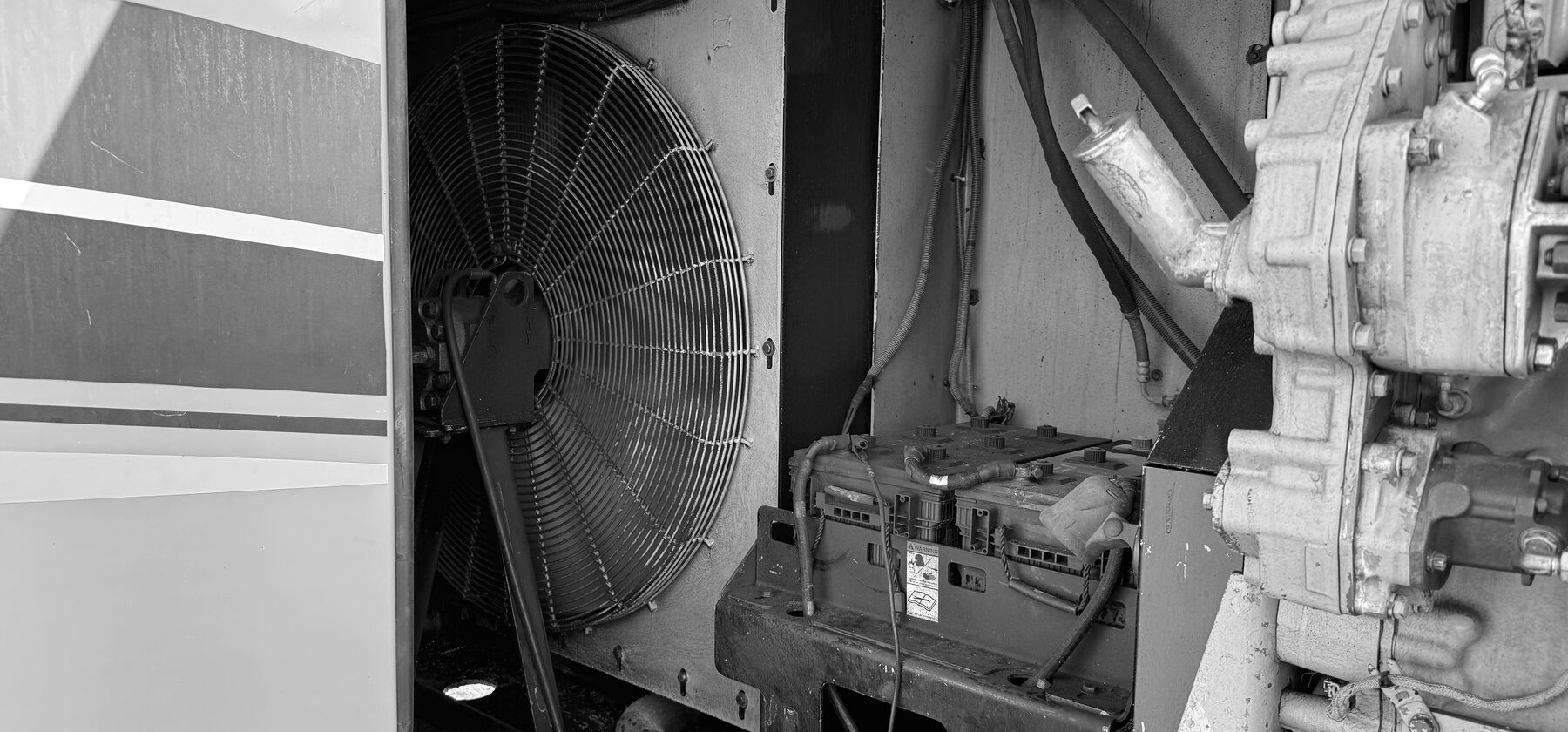 A cooling fan, battery box, and gearbox crowded into a drill rig's engine bay