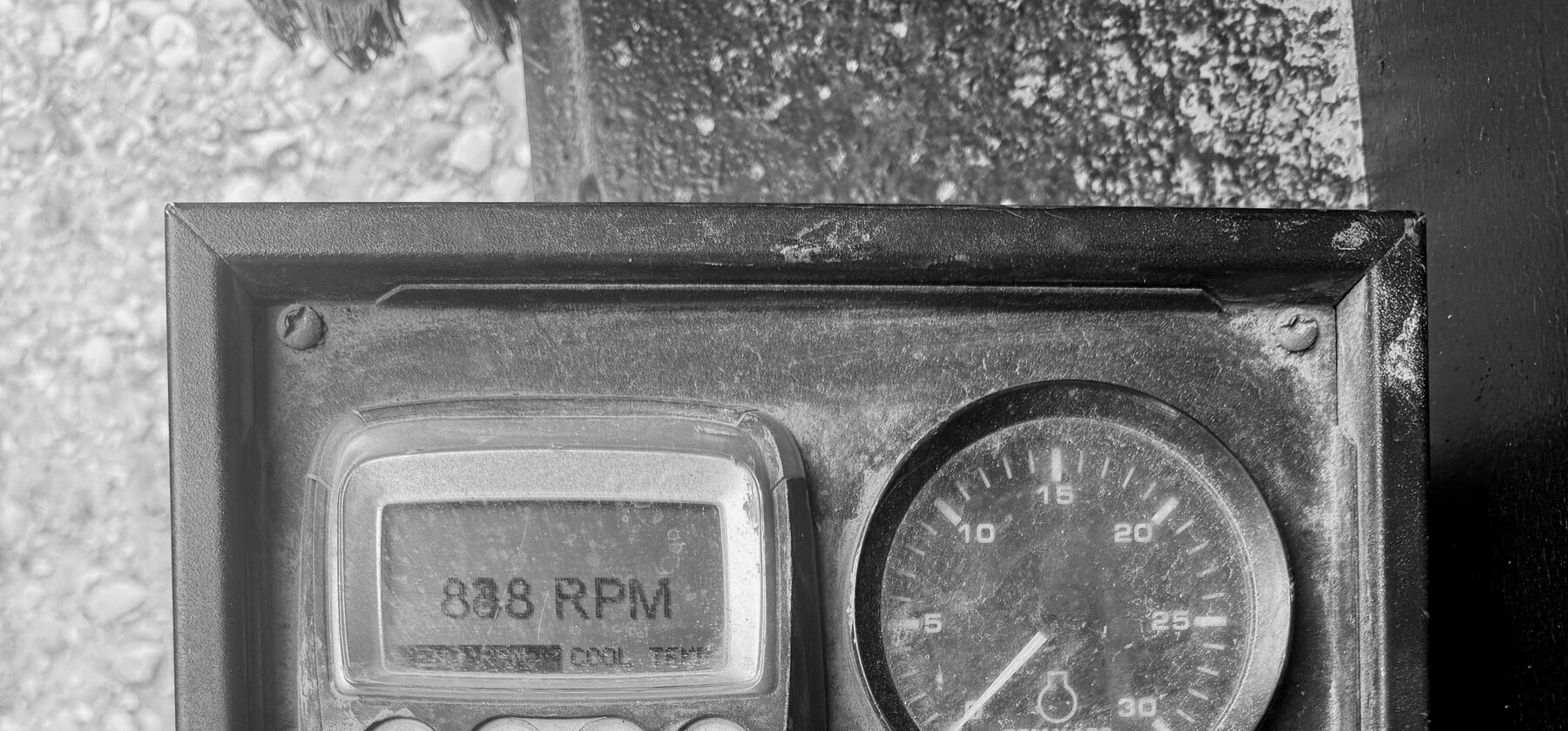 A digital RPM readout and analog tachometer on a wheel trencher's instrument panel