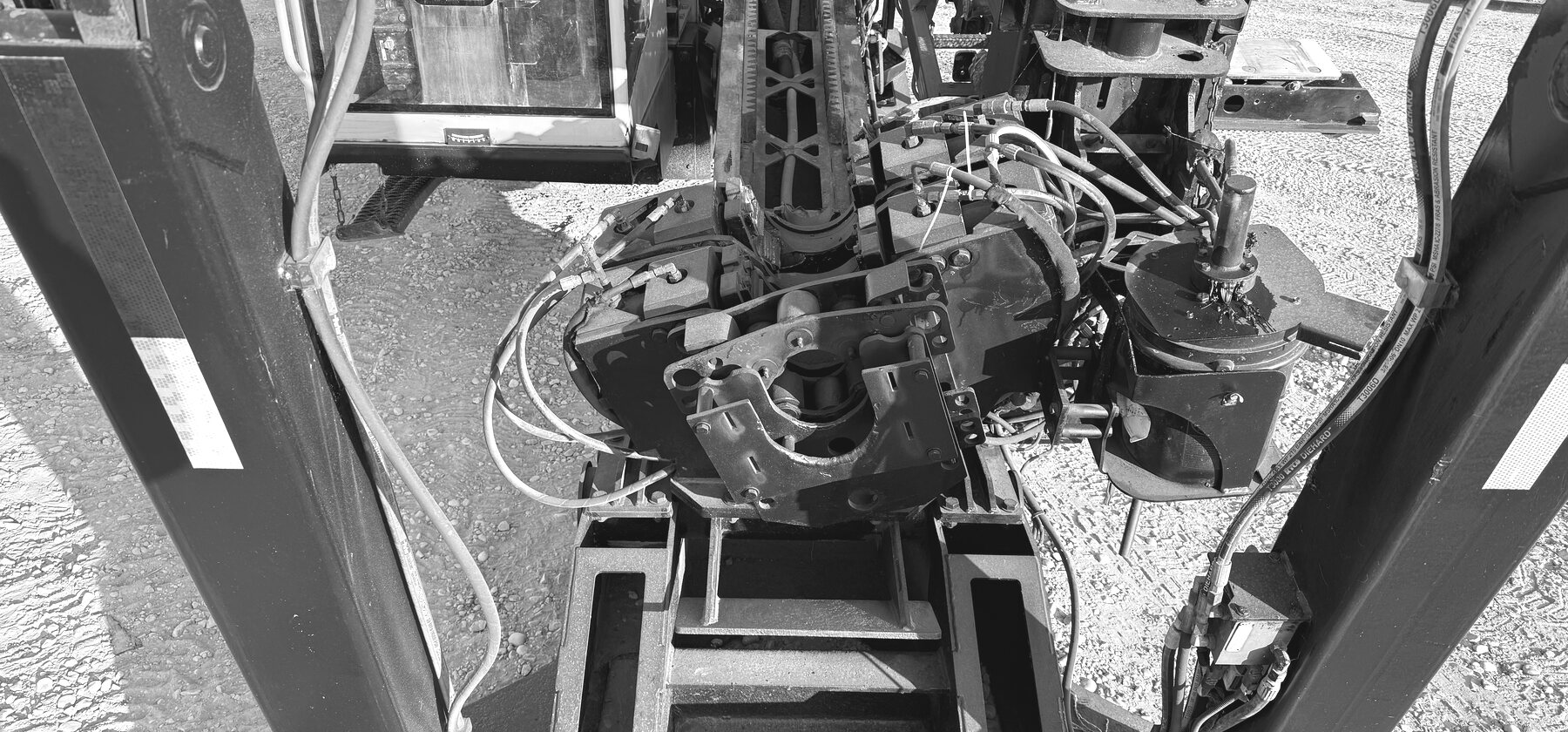 A top-down view of a horizontal directional drill's rotary-head hydraulics and mounting hardware, cab door visible behind
