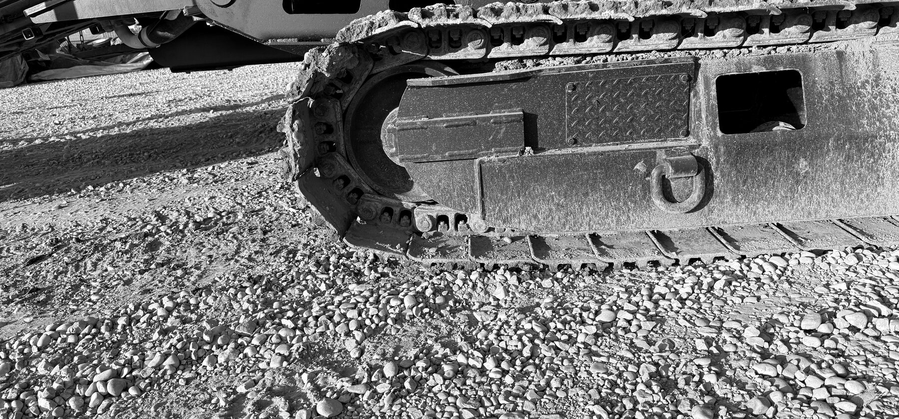 A track chain, roller, and sprocket packed with dried ground on a drill rig's undercarriage