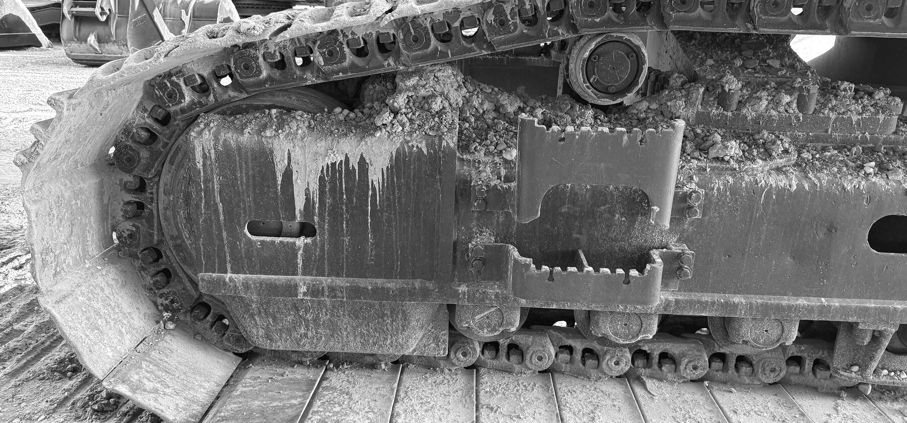 An excavator idler wheel and track chain caked in dried mud