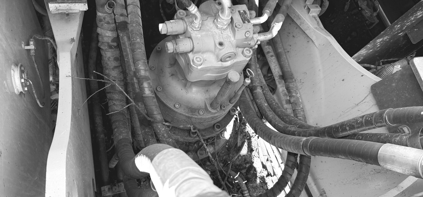 A hydraulic swing pump with hoses radiating outward in an excavator engine bay