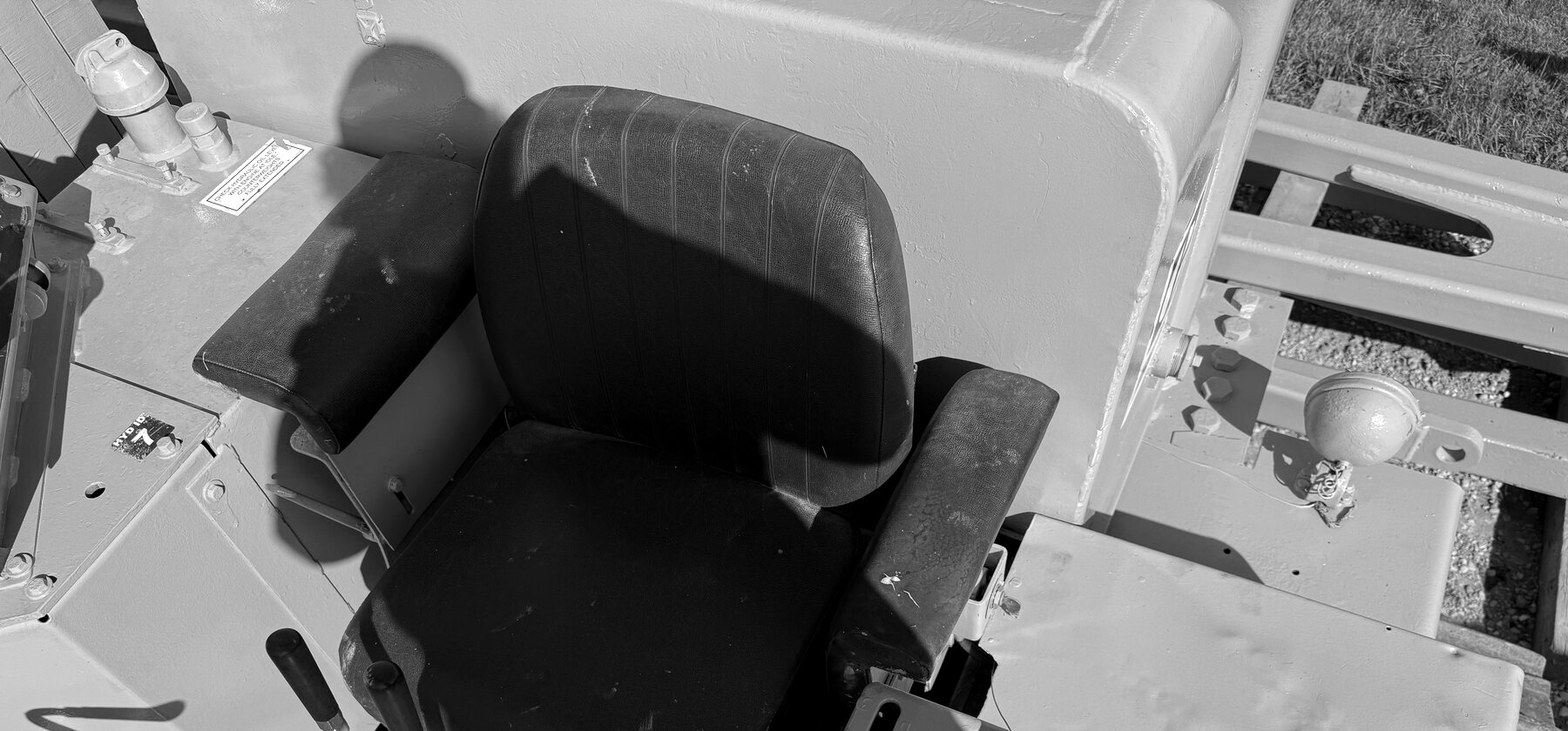 Overhead view of a side boom's operator seat, armrests and foot pedals in the open control station